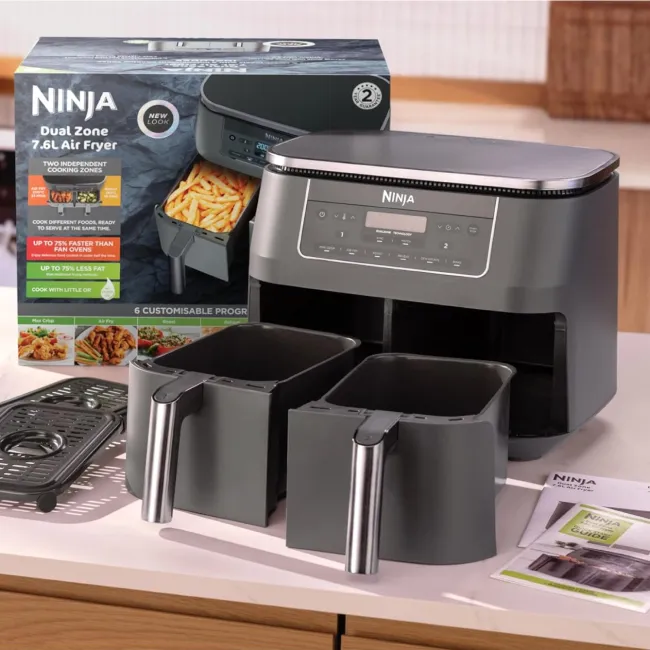 Le Ninja Airfryer 2 bacs avec les bacs mis en évidence, ainsi que ses fonds troués sortis des bacs et mis sur le côté.