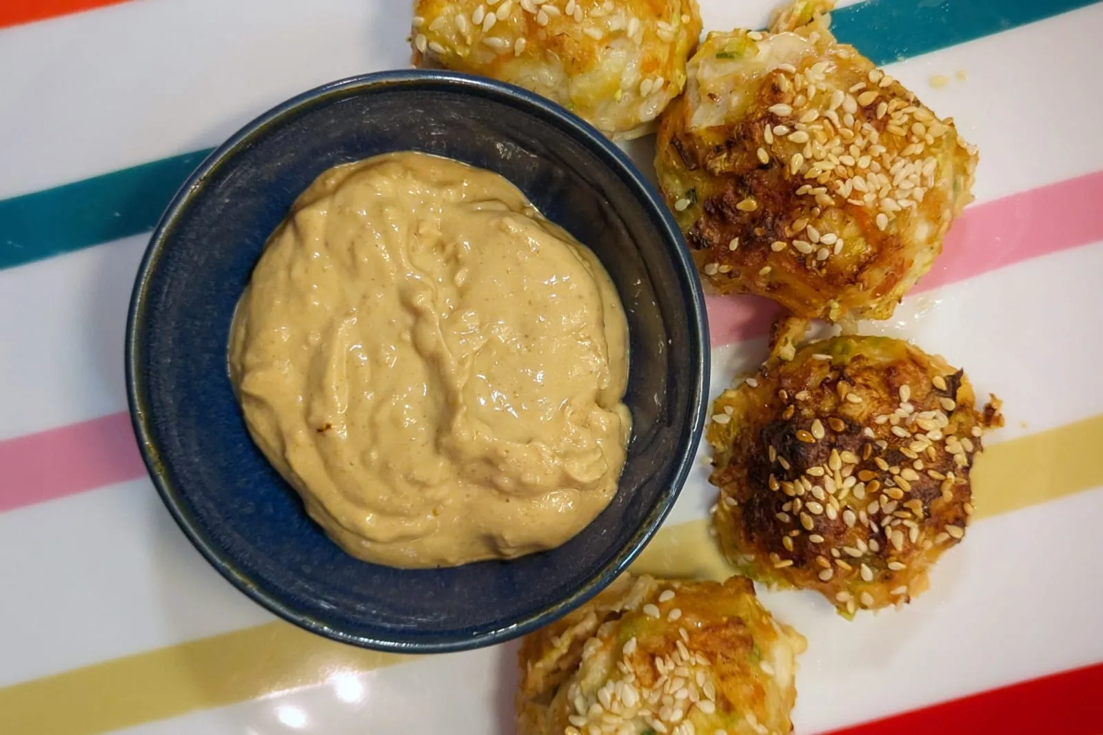 4 boulettes de poulet dorées avec des graines de sésame, et une sauce cremeuse au milieu